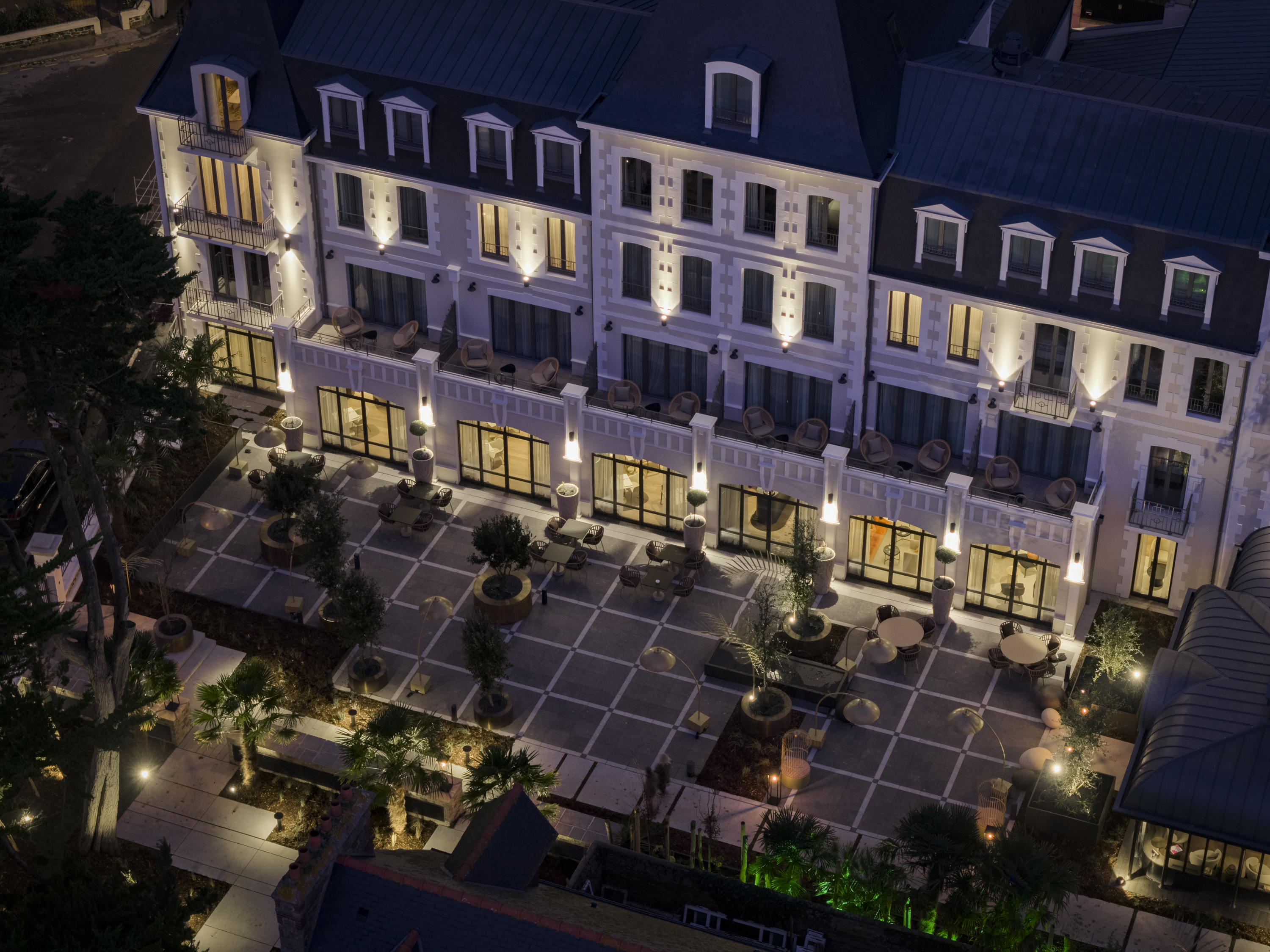 Facade with furnished terrace and armchairs of the Grand Hotel de Courtoisville in Saint-Malo, a 4-star spa hotel by the sea.