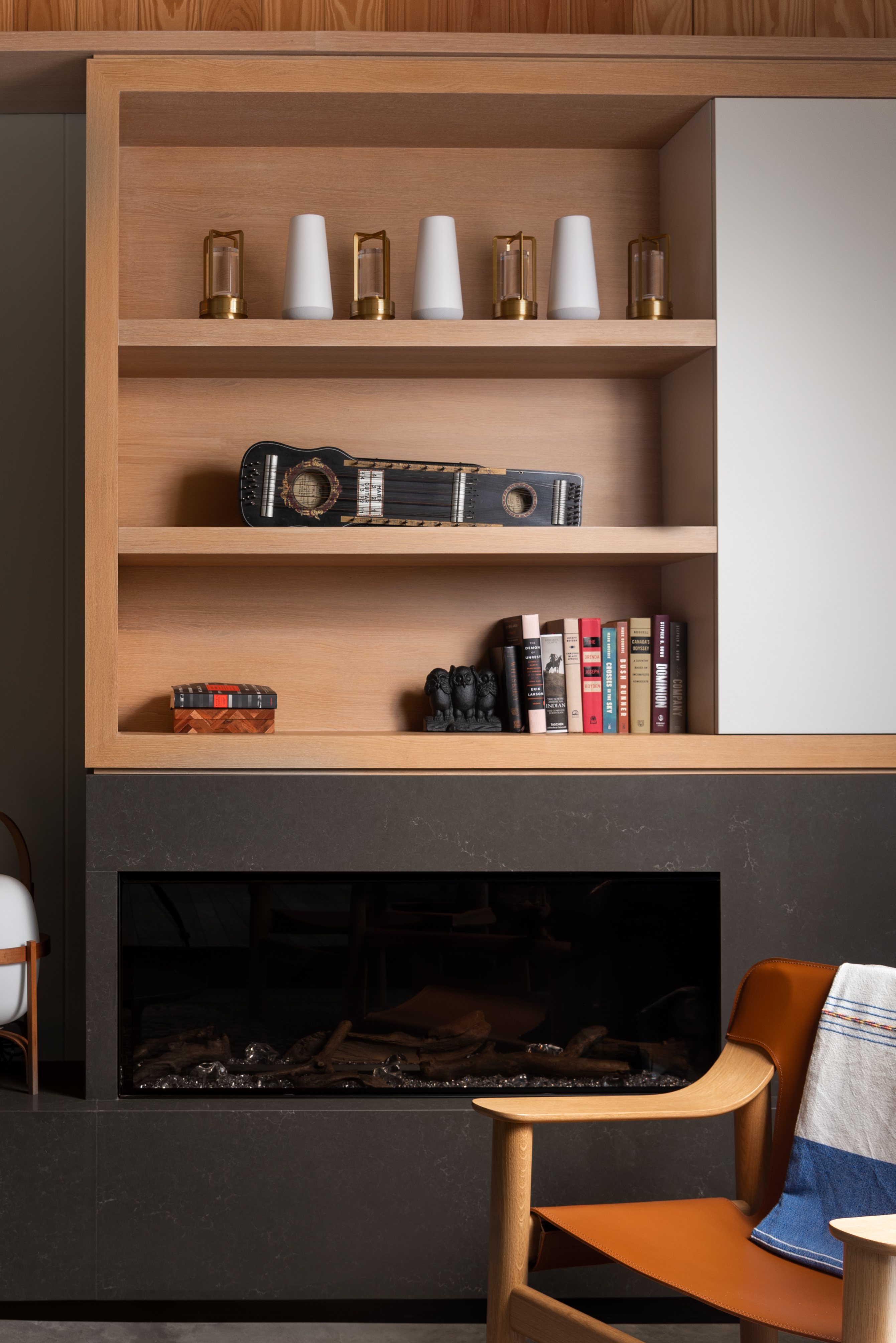 Modern office lounge featuring custom millwork shelving with books, decor, and a guitar, highlighting Goosen Inc.'s craftsmanship in a welcoming workspace.