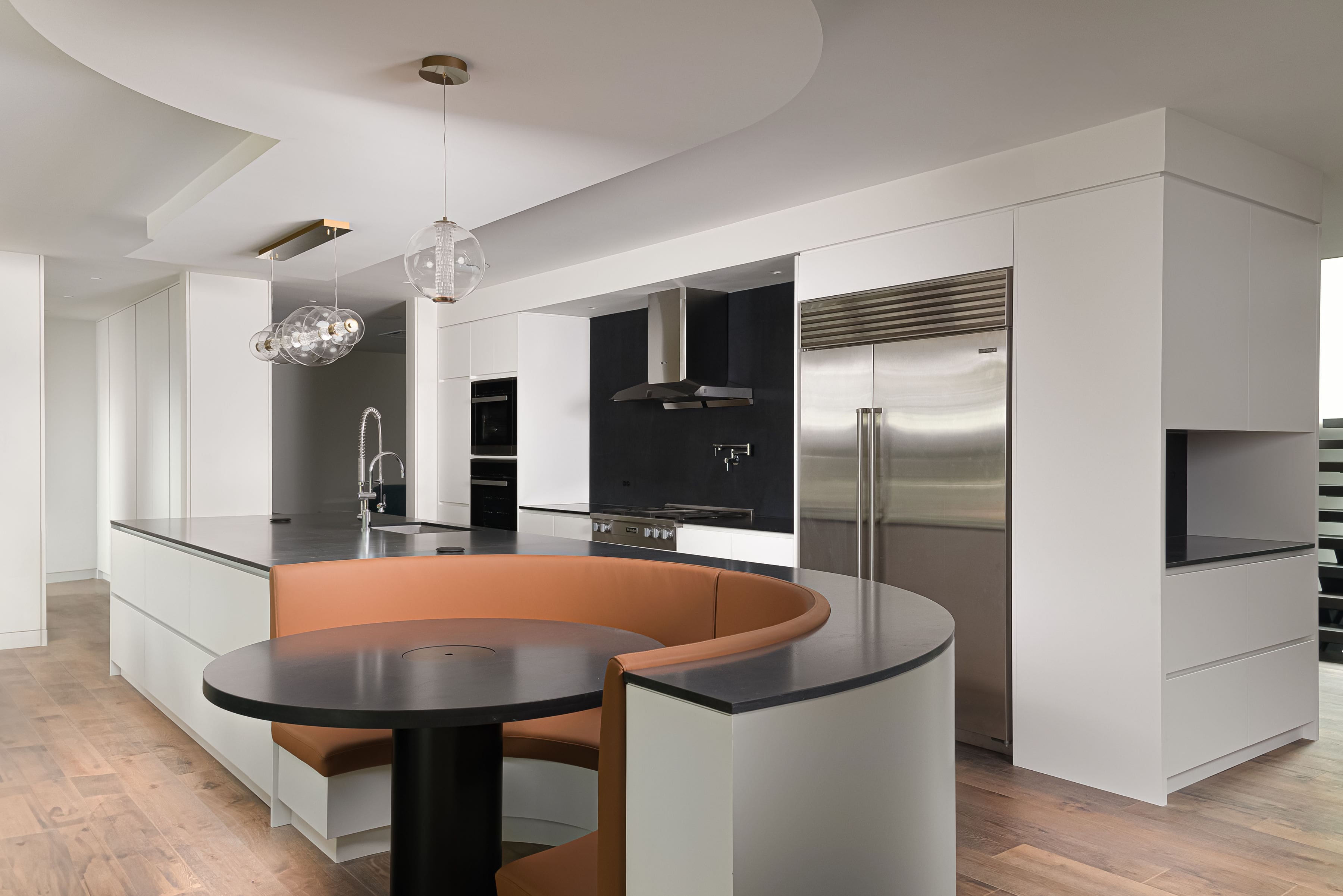 Contemporary kitchen interior with custom curved seating, premium cabinetry, and modern lighting, showcasing Goosen Inc.’s blend of innovative millwork and elegant design.