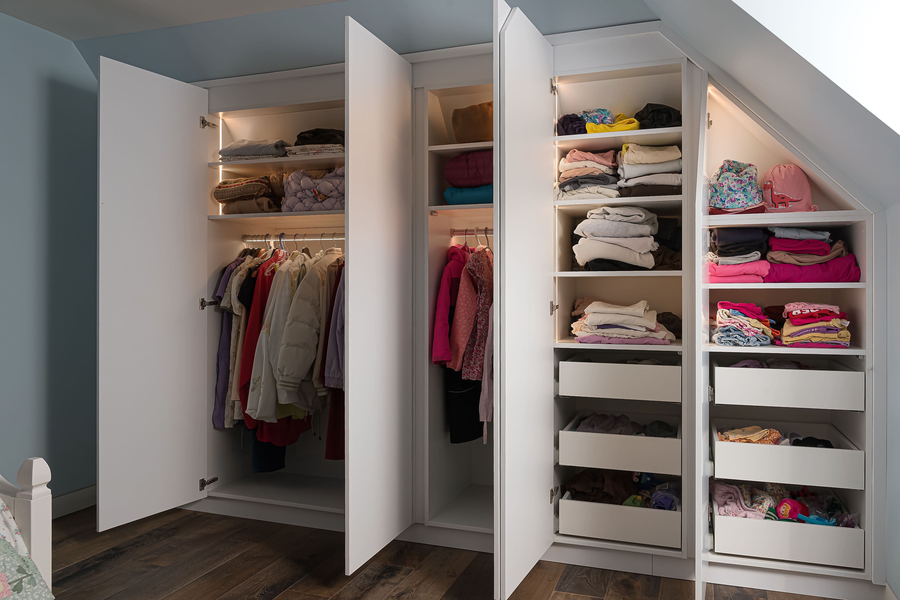 Built-in wardrobe with open doors revealing organized shelves, drawers, and hanging space, showcasing Goosen Inc.'s custom storage solutions.