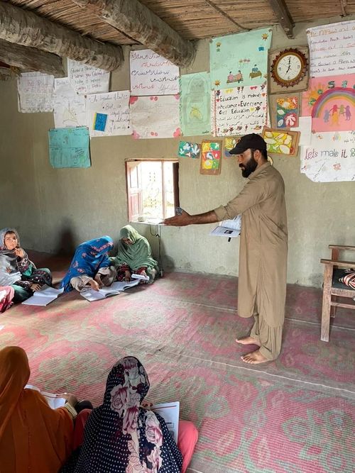 Teacher, students listening while sitting on floor mats