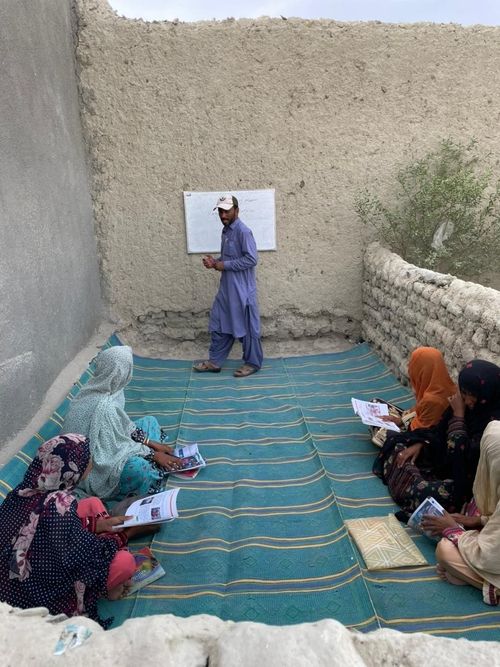 Teacher, students sitting on floor mats
