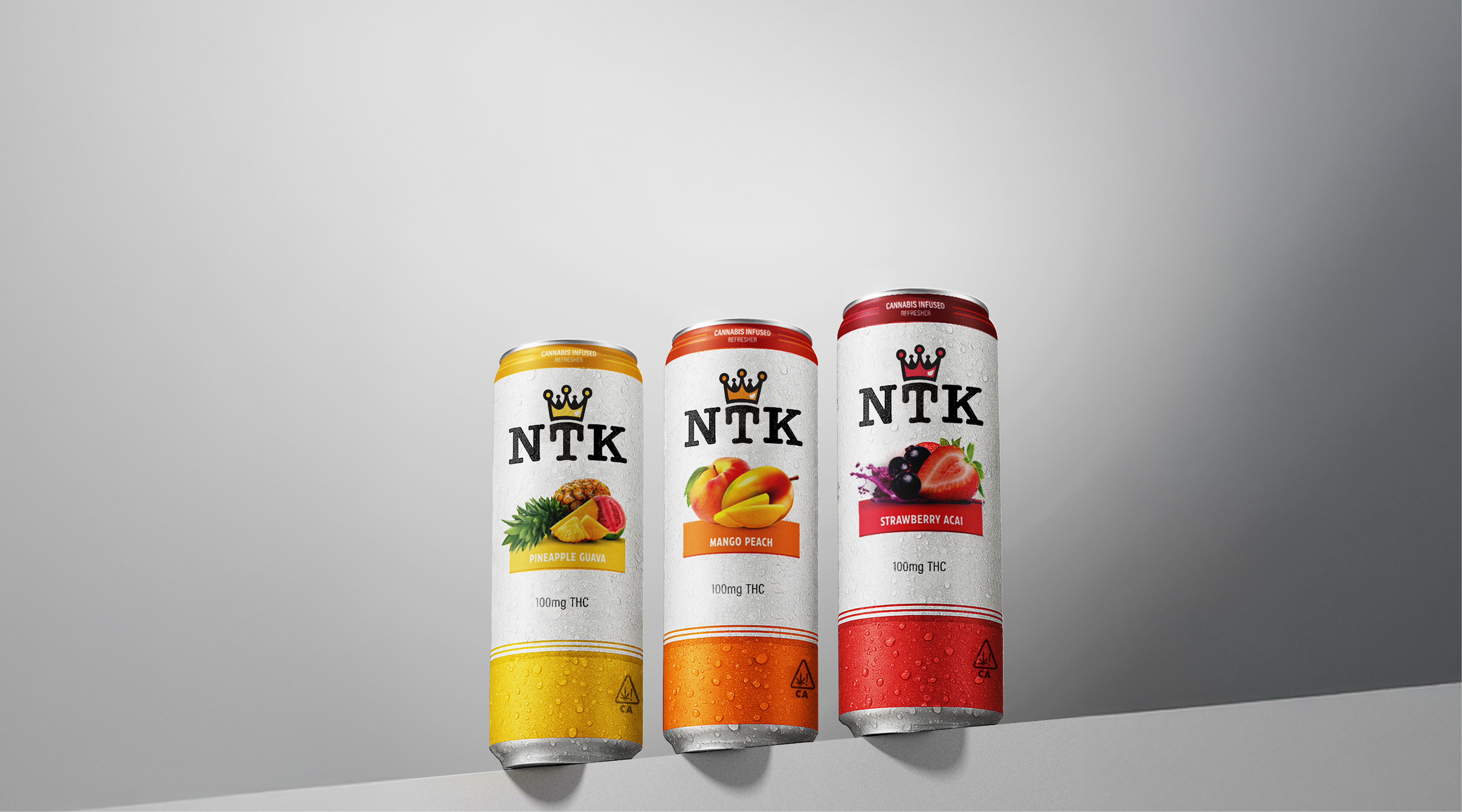Three tall NTK cannabis-infused drink cans in pineapple guava, mango peach, and strawberry acai flavors are displayed side by side against a gray background.