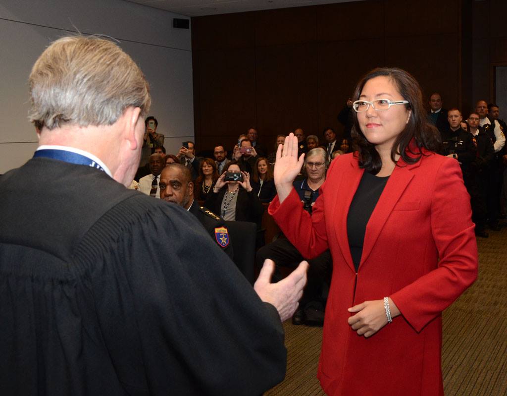 Holly Kim with her hand raised being sworn in by a judge