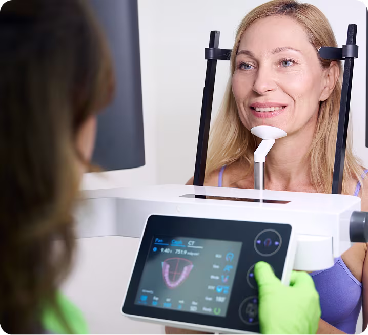 A woman undergoing a dental X-ray or CT scan procedure, with a dental professional operating the machine.