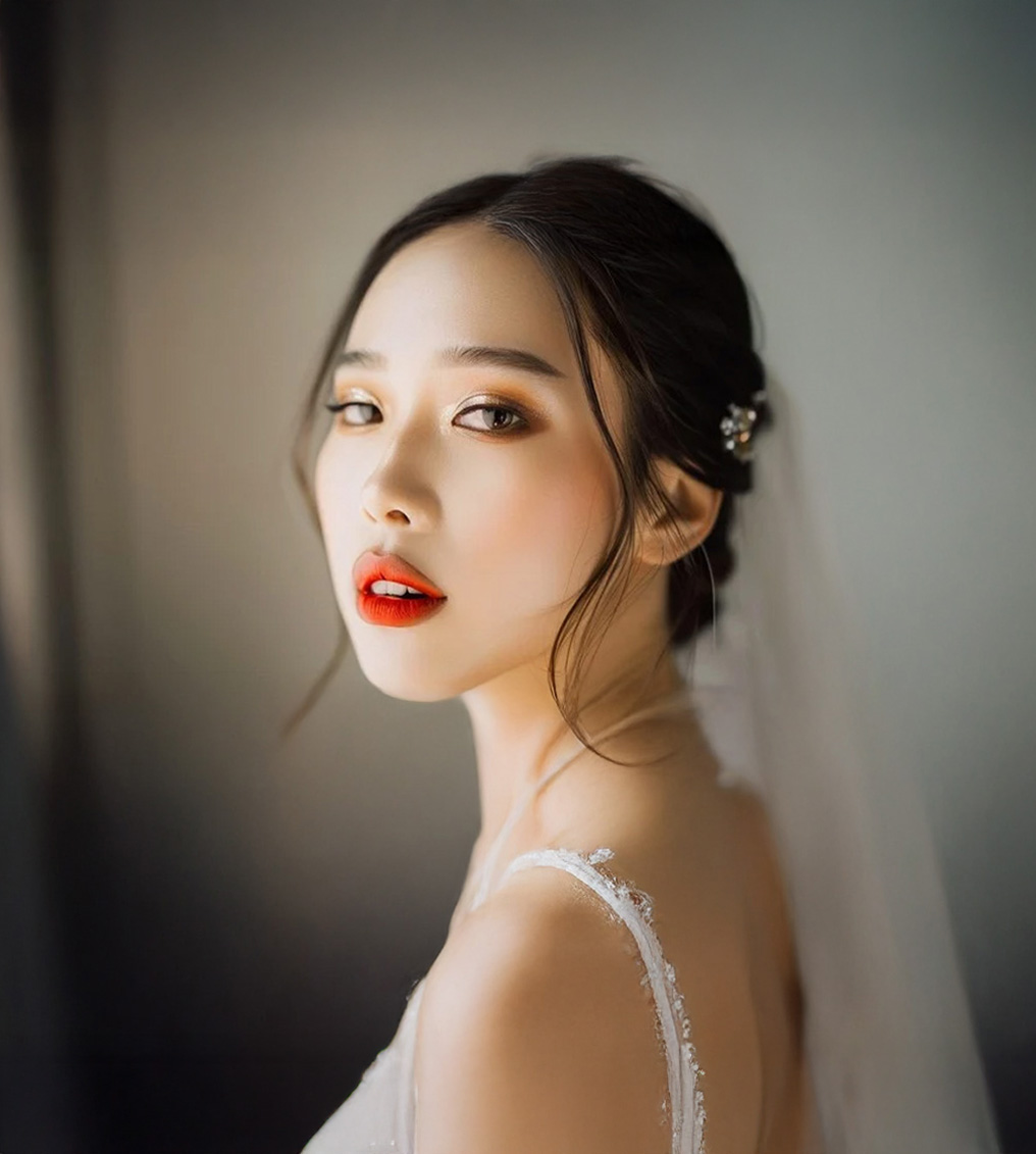 Young woman with elegant makeup and red lipstick wearing a white lace strap dress and hair accessory.