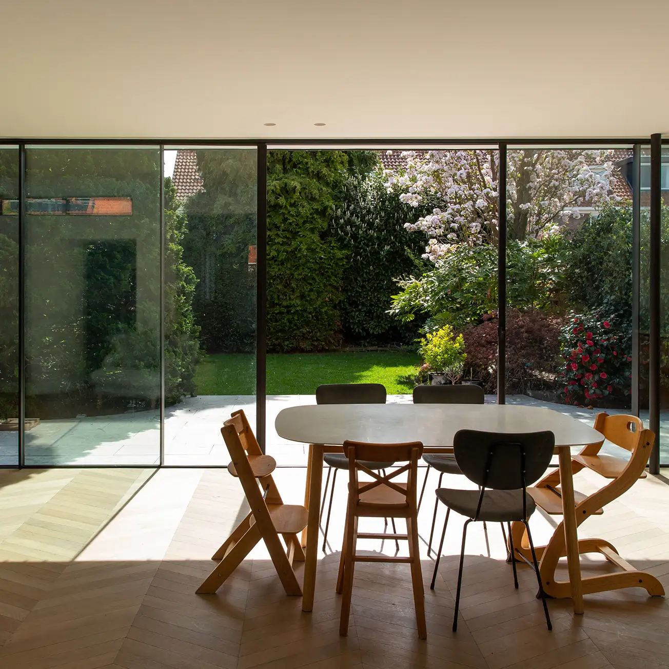 Modern house with white and wood-paneled exterior, surrounded by a garden pond and patio with outdoor seating.