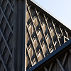 Close-up of a modern architectural structure with intersecting wooden beams forming a geometric pattern with triangular openings.