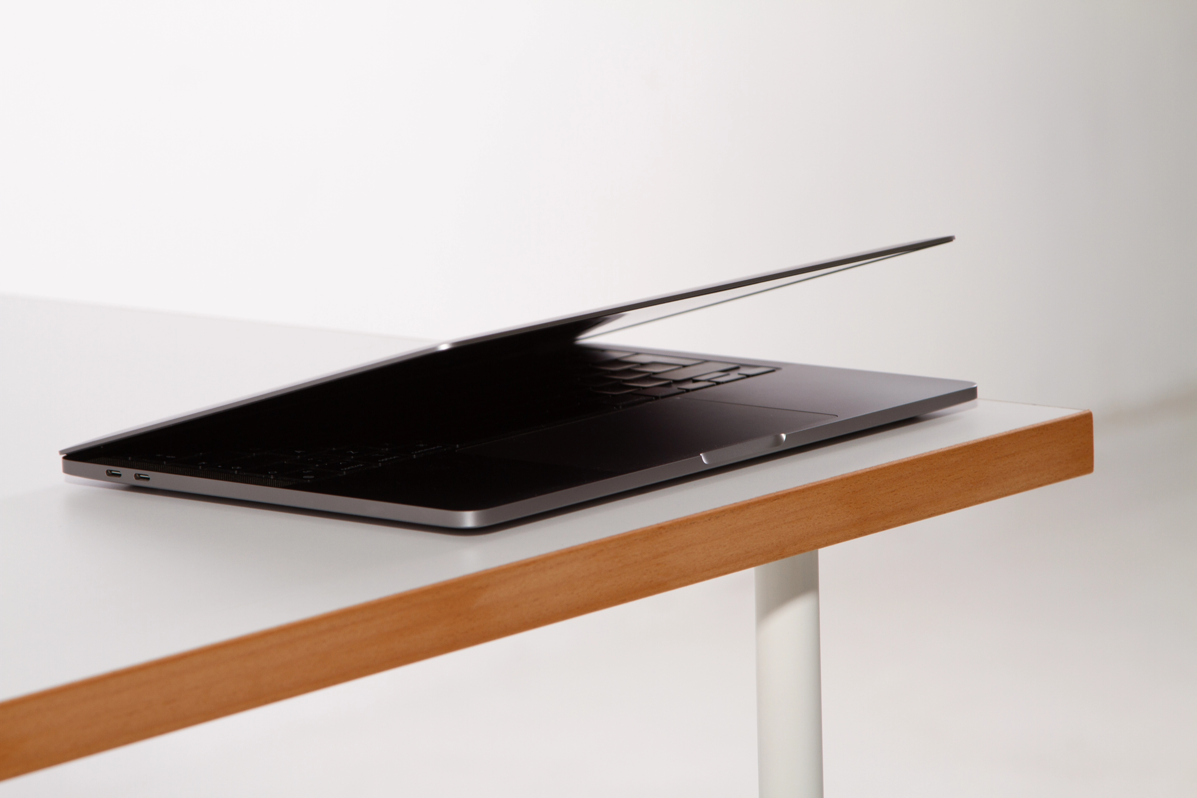 Uchylony laptop leżący na krawędzi biurka z drewnianym blatem
