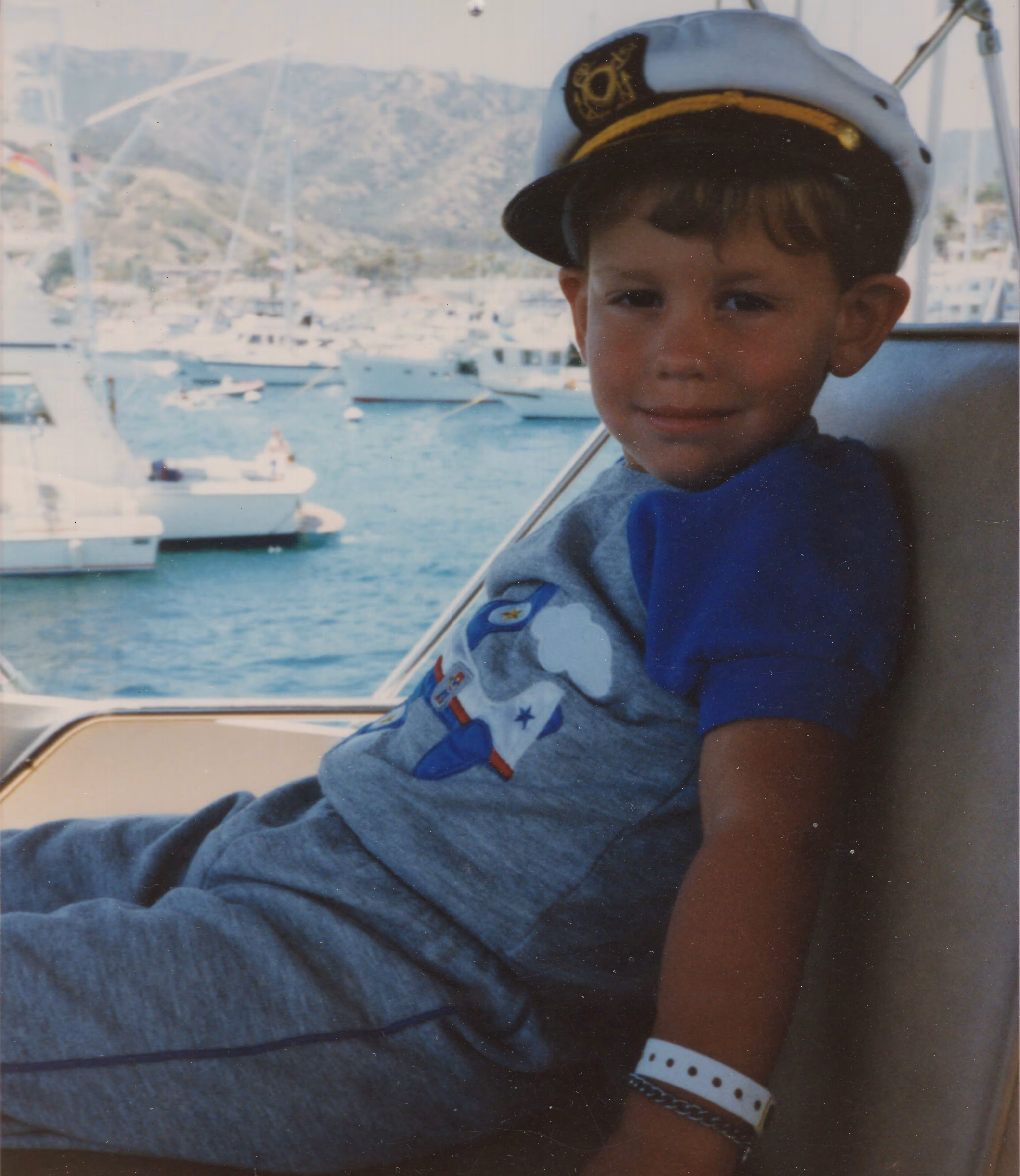 Young Nicholas sitting on a boat wearing a captain's hat.