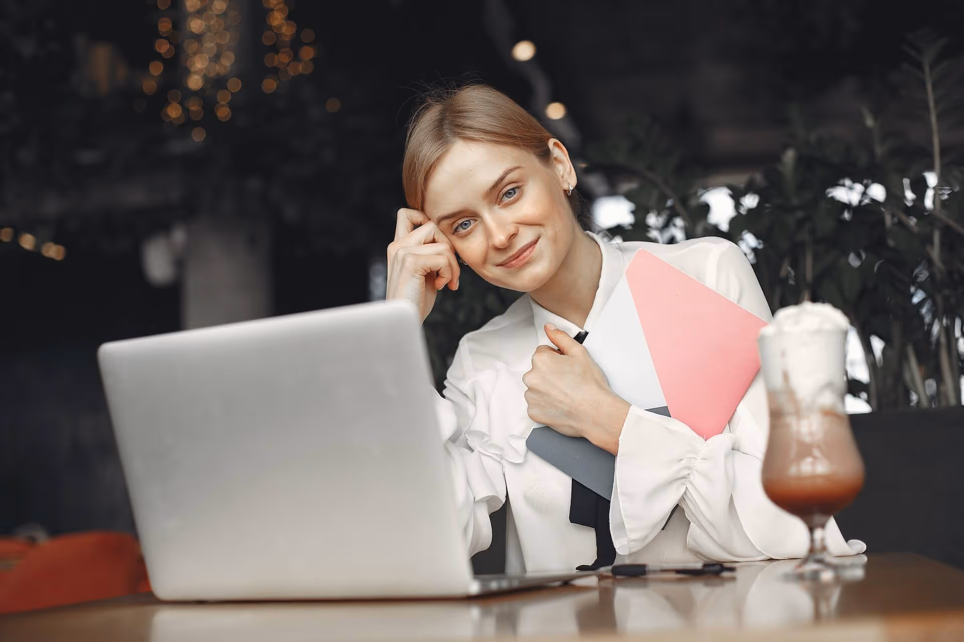 A woman with a laptop and a pink folder.