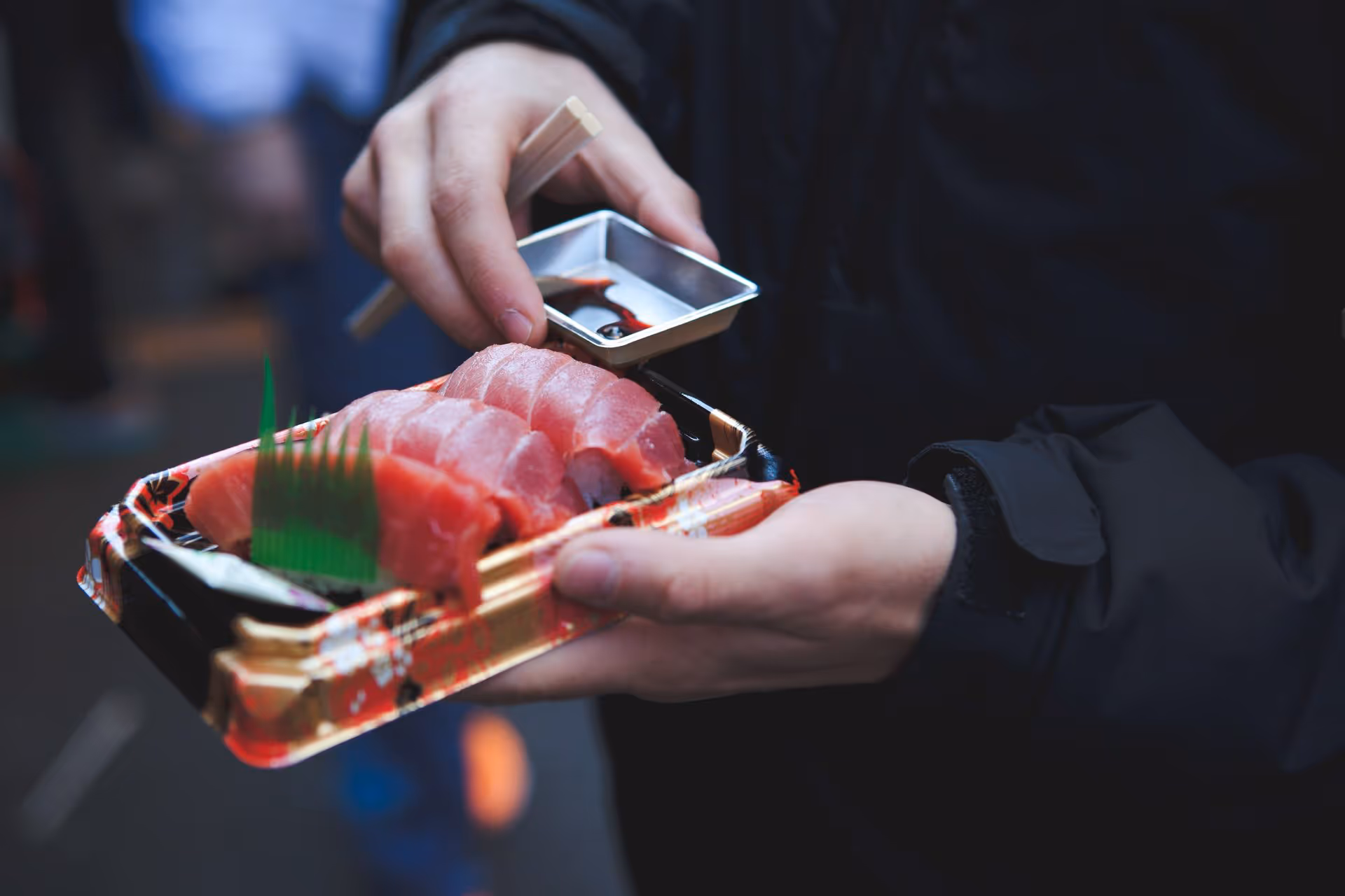 Plakjes rauwe sashimi-tonijn, vakkundig gegarneerd met groene kruiden, in een luxe gouden schaal.
