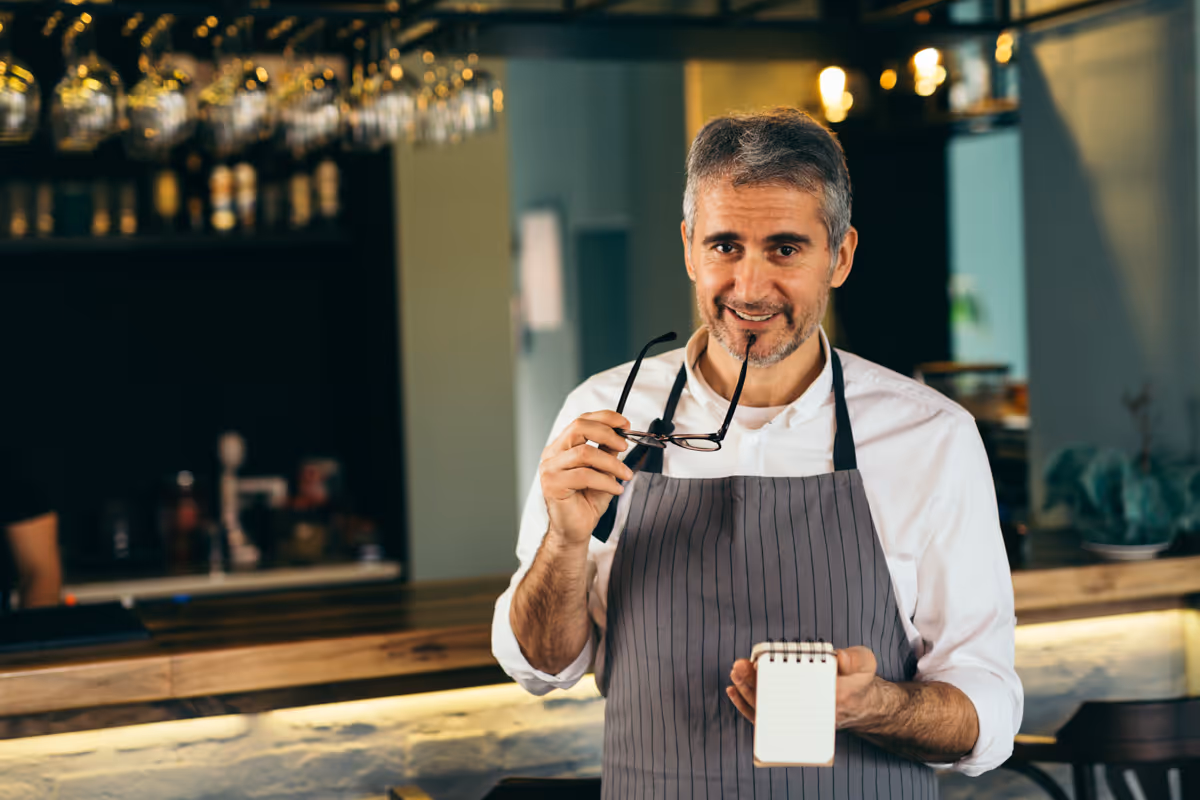 Koffiebarscène met een lachende man met een schort en een warme kop.