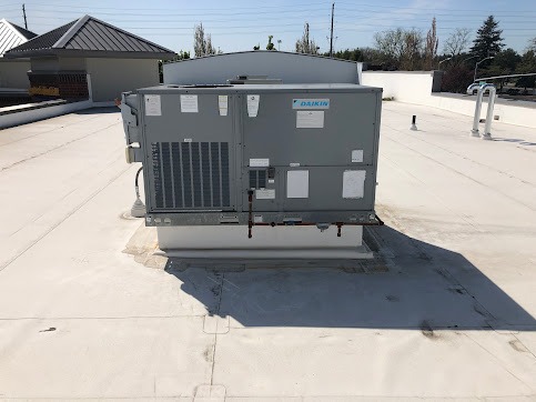 Large gray HVAC unit sitting on a flat white roof with power lines