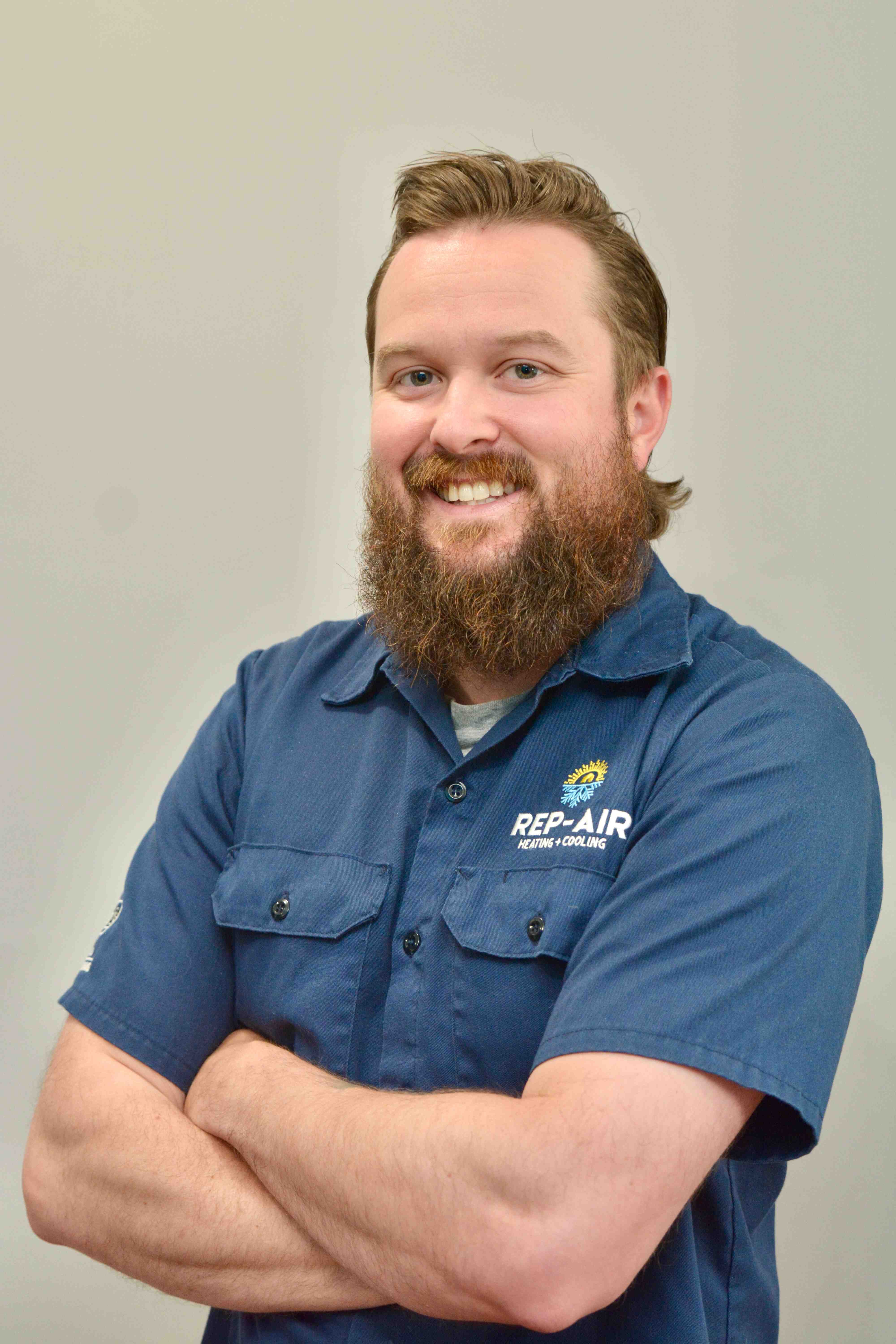Smiling technician in blue Rep-Air uniform with crossed arms