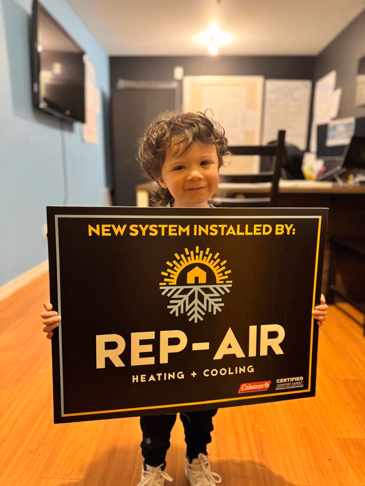 Smiling child holding Rep-Air Heating + Cooling installation sign