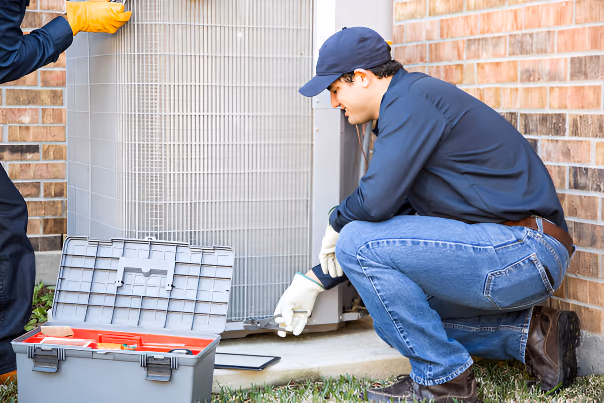 HVAC technician repairing air conditioning unit outside brick building
