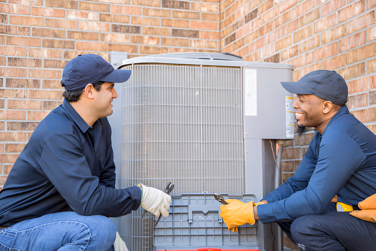 Two technicians working together on an outdoor HVAC unit