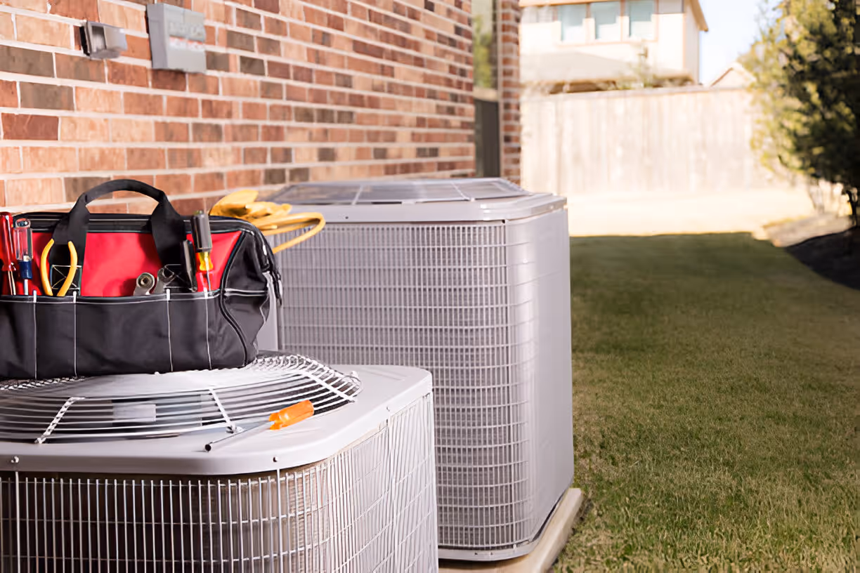 HVAC technician's tool bag next to air conditioning units outdoors