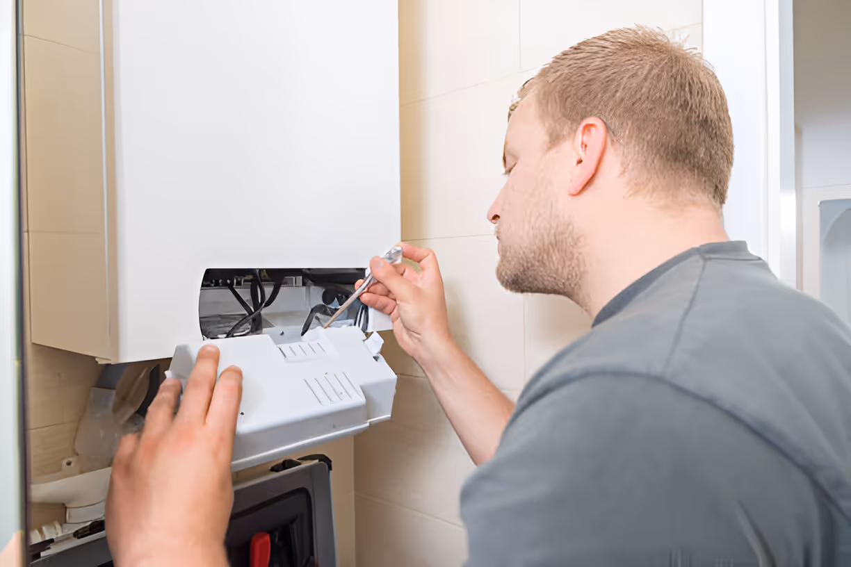 Technician repairing or maintaining a wall-mounted heating or electrical system