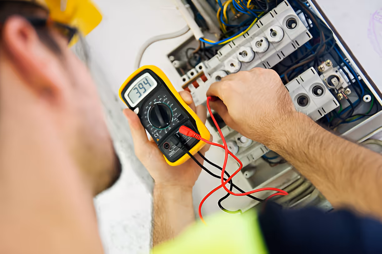 Electrician using multimeter to test voltage in electrical panel