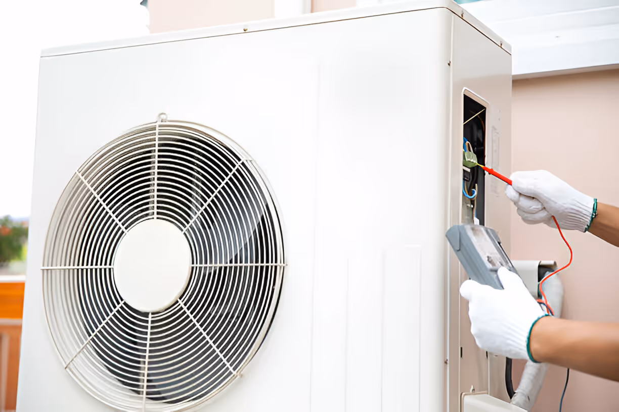 Technician repairs air conditioning unit with electrical testing equipment