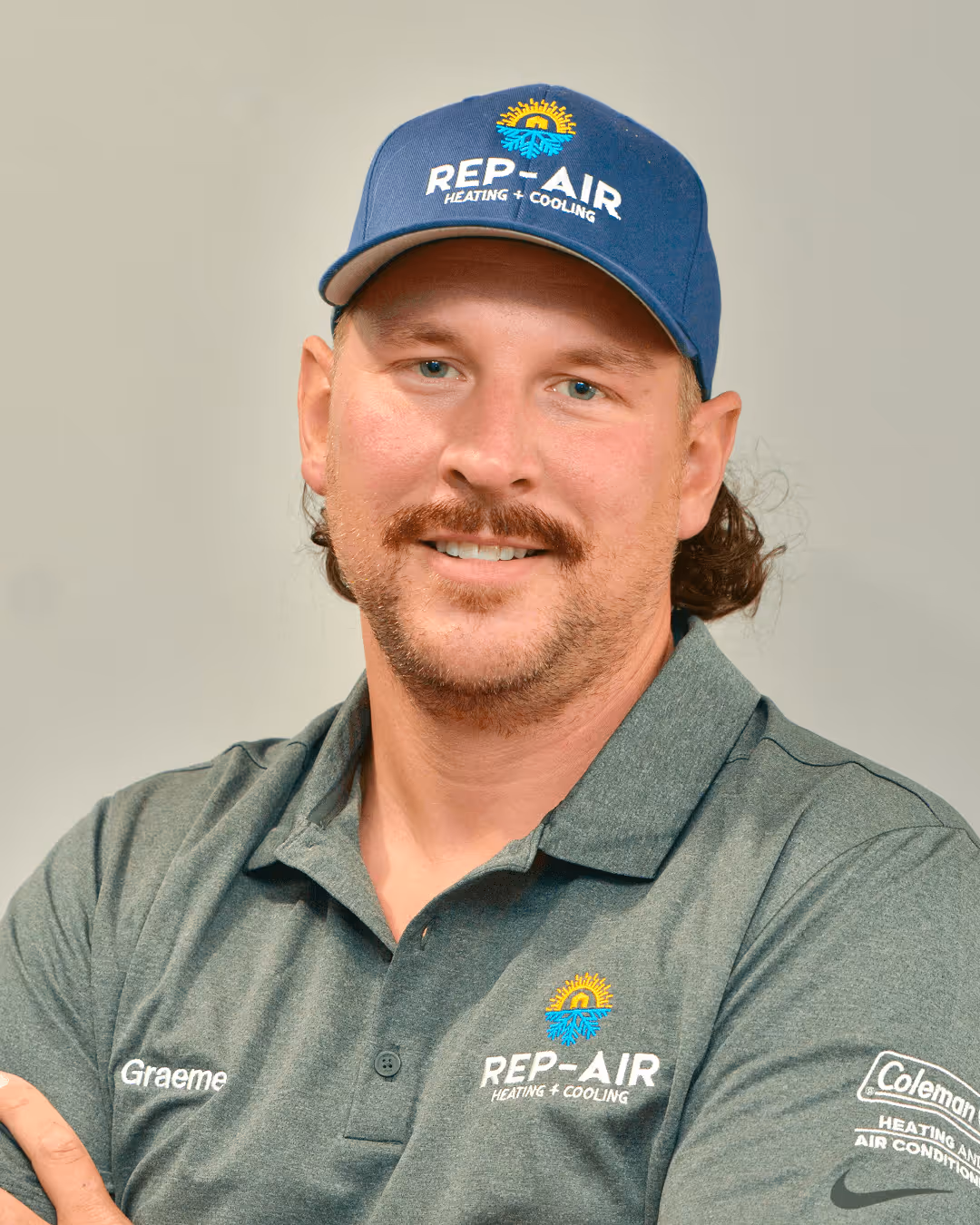 Smiling HVAC technician in blue cap and gray Rep-Air company shirt