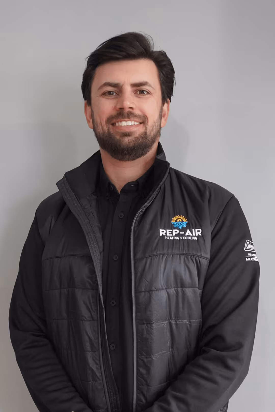 Smiling technician in Rep-Air Heating and Cooling branded jacket