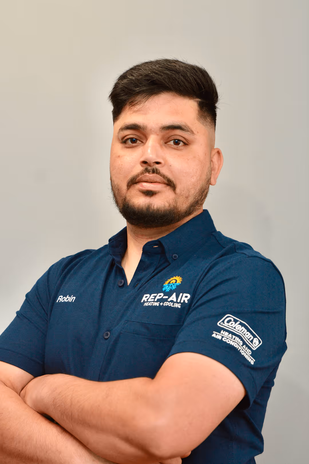 HVAC technician in blue Rep-Air uniform with crossed arms