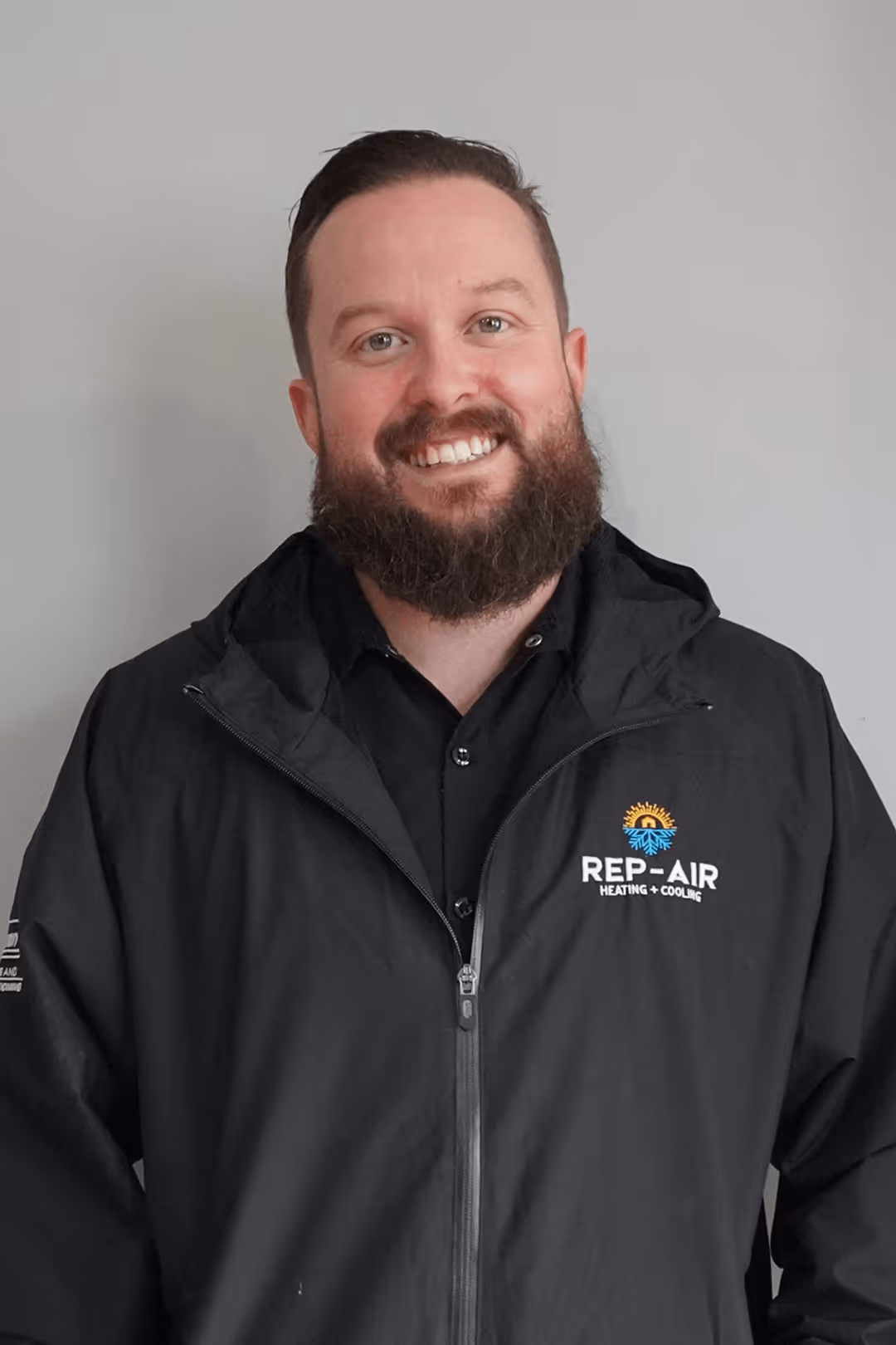 Smiling bearded technician wearing Rep-Air Heating and Cooling jacket