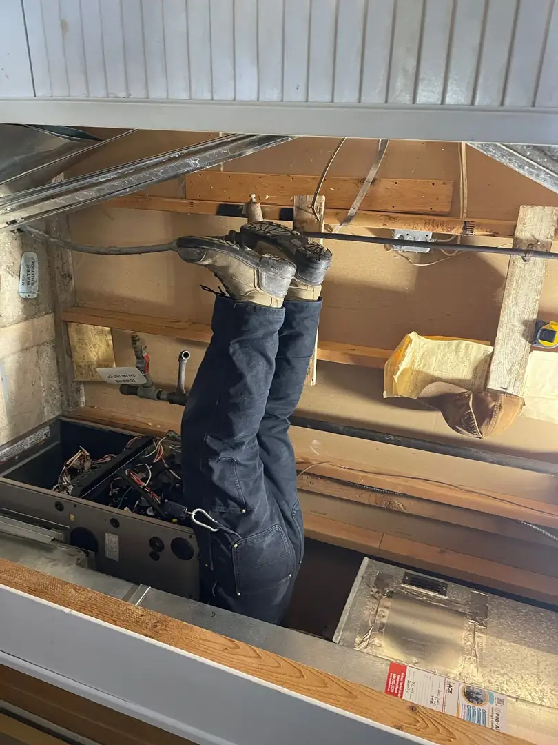 An HVAC technician carefully inspecting an indoor furnace and evaporator coil setup An HVAC technician carefully inspecting an indoor furnace and evaporator coil setup