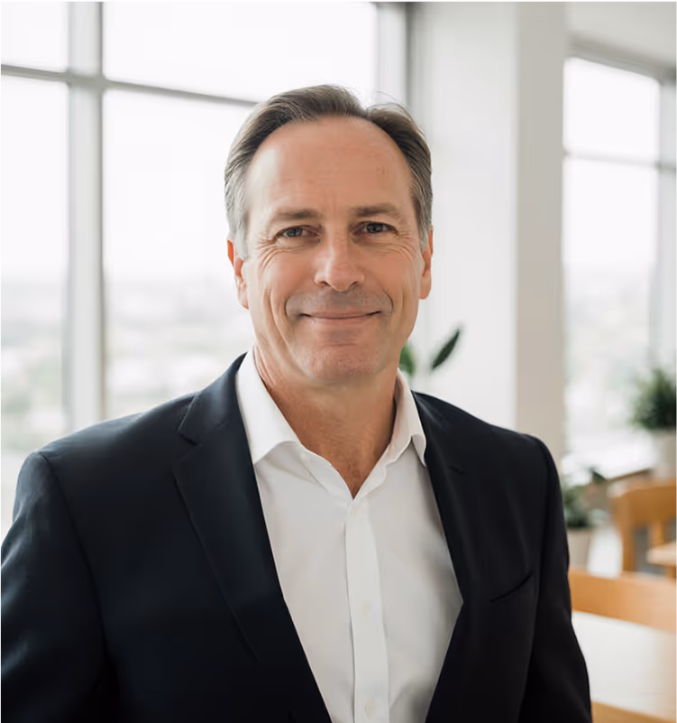 Portrait d’un dirigeant en costume noir, assis dans un bureau contemporain, visage calme et professionnel, illustrant la confiance d’un client corporate.