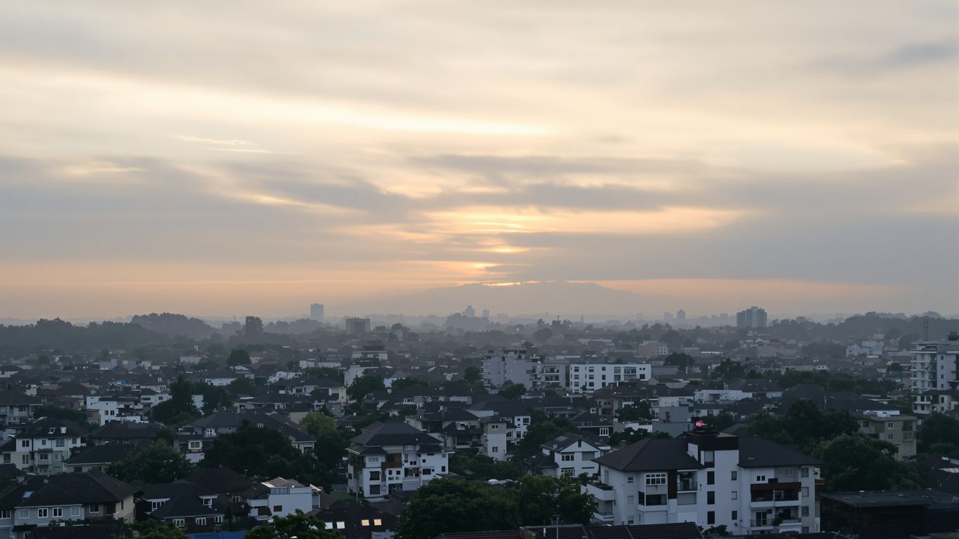 Cityscape with sunrise breaking through clouds.