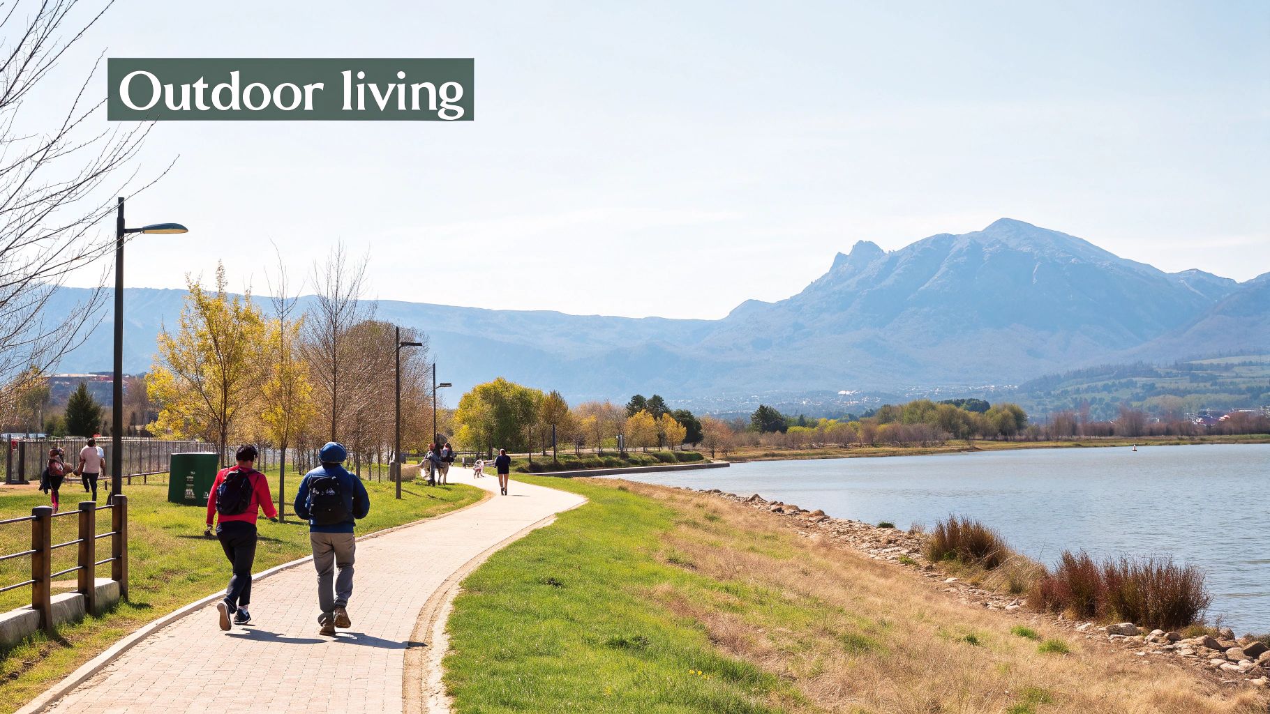Two people exercising on a paved path alongside a lake with scenic mountains in the distance.