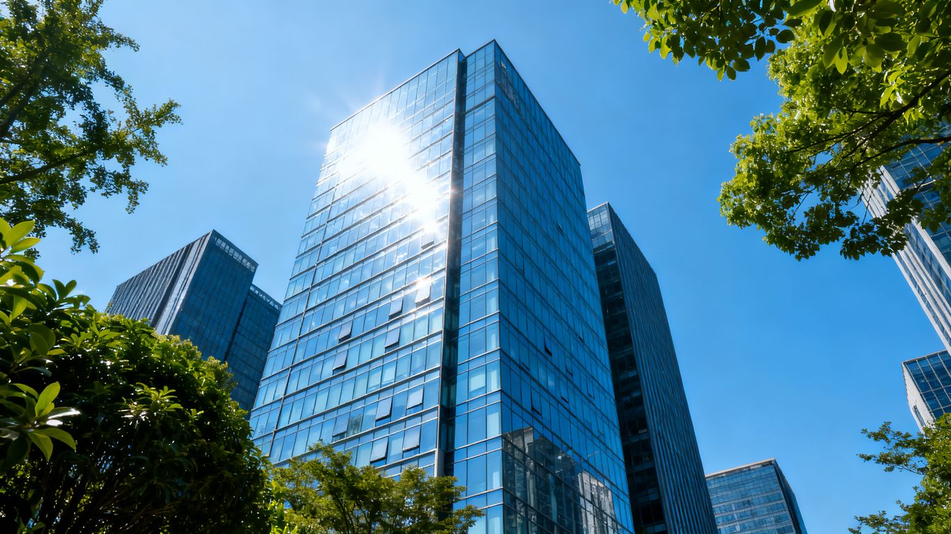 Modern office building exterior with glass facade and blue sky.