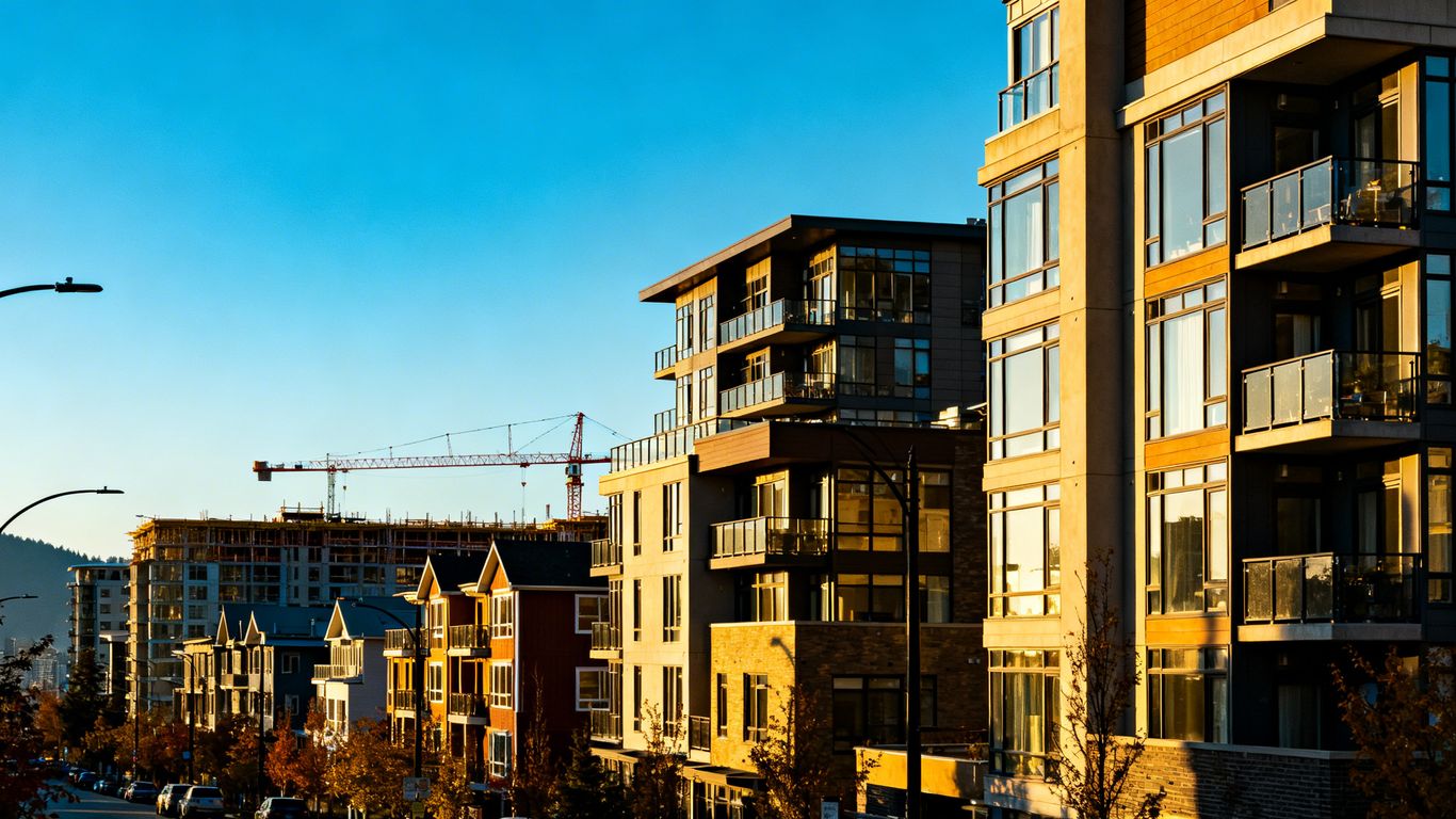 Vancouver apartment buildings and construction cranes under a blue sky.