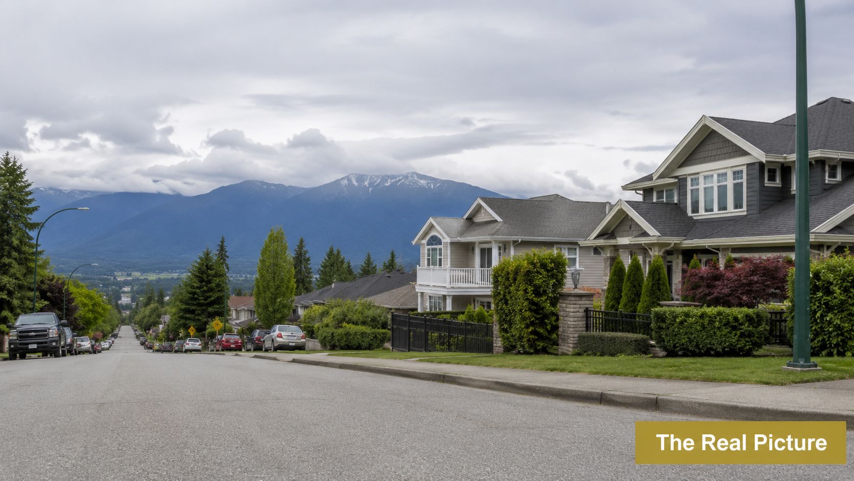 A quiet residential street in Mission, British Columbia, featuring beautiful mountain views under a cloudy sky.
