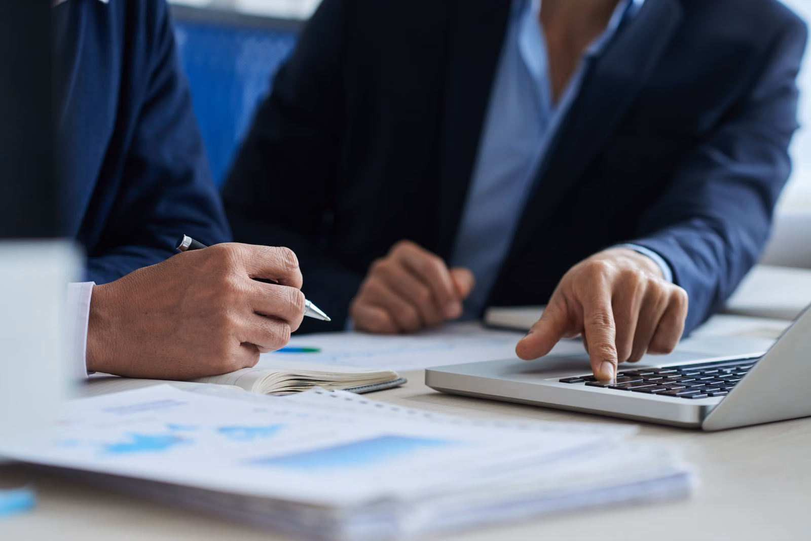 Two advisors reviewing financial charts and a laptop during a credit assessment meeting