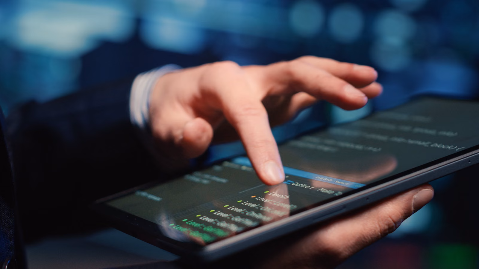Hand tapping a tablet showing a claims document table in a dark office