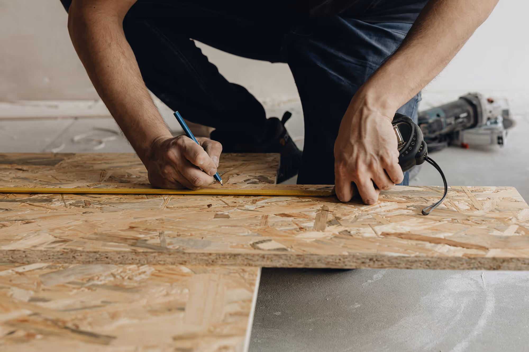 Two hands measuring plywood