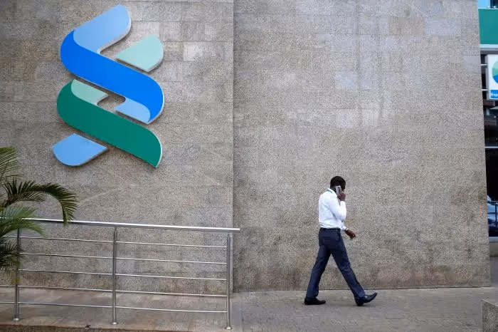 A man walks past a Standard Chartered Bank.