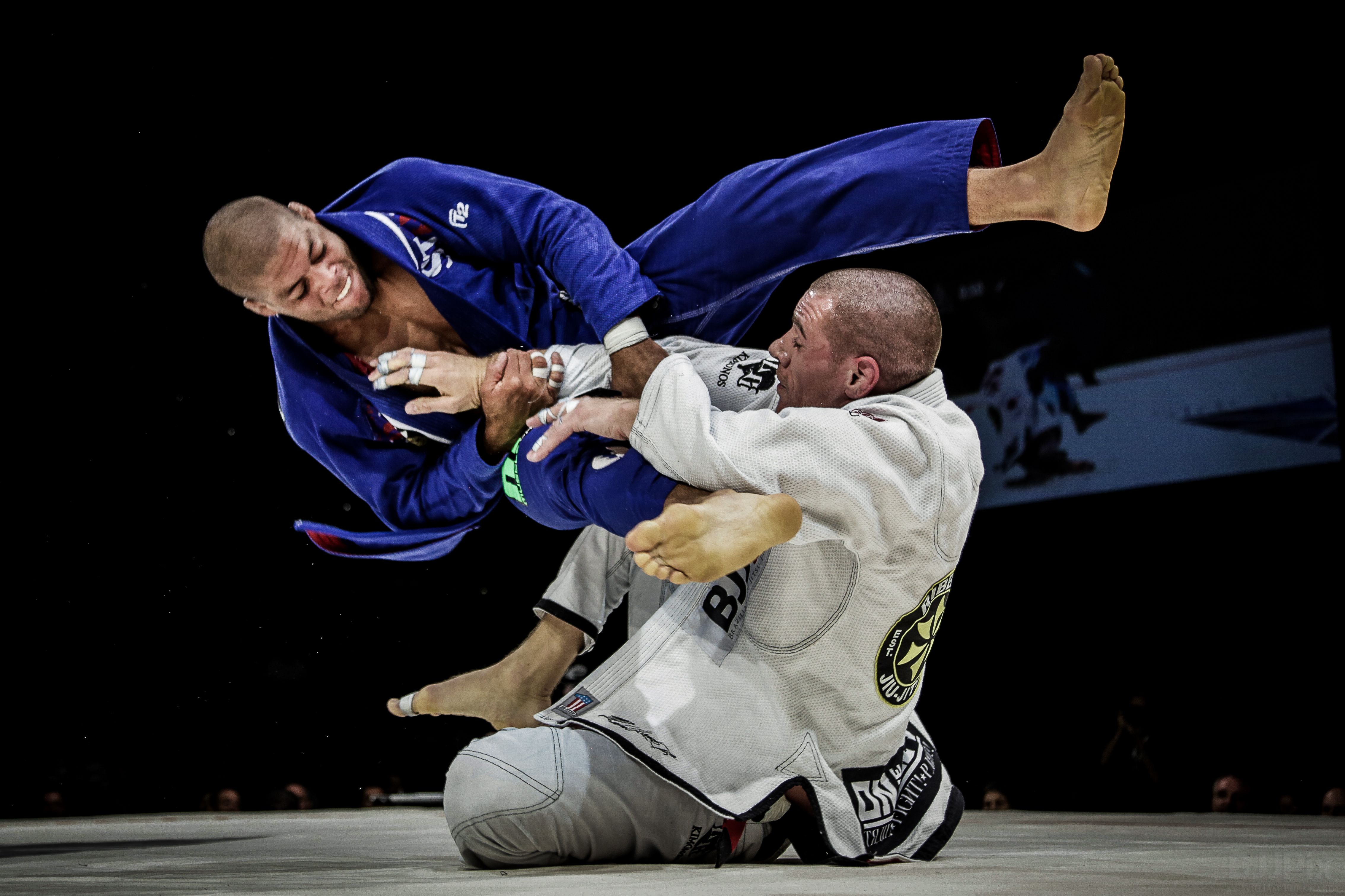 Alt text conseillé : Combat de Jiu-Jitsu Brésilien en Gi illustrant l’utilisation des leviers, des appuis et de la technique au sol.