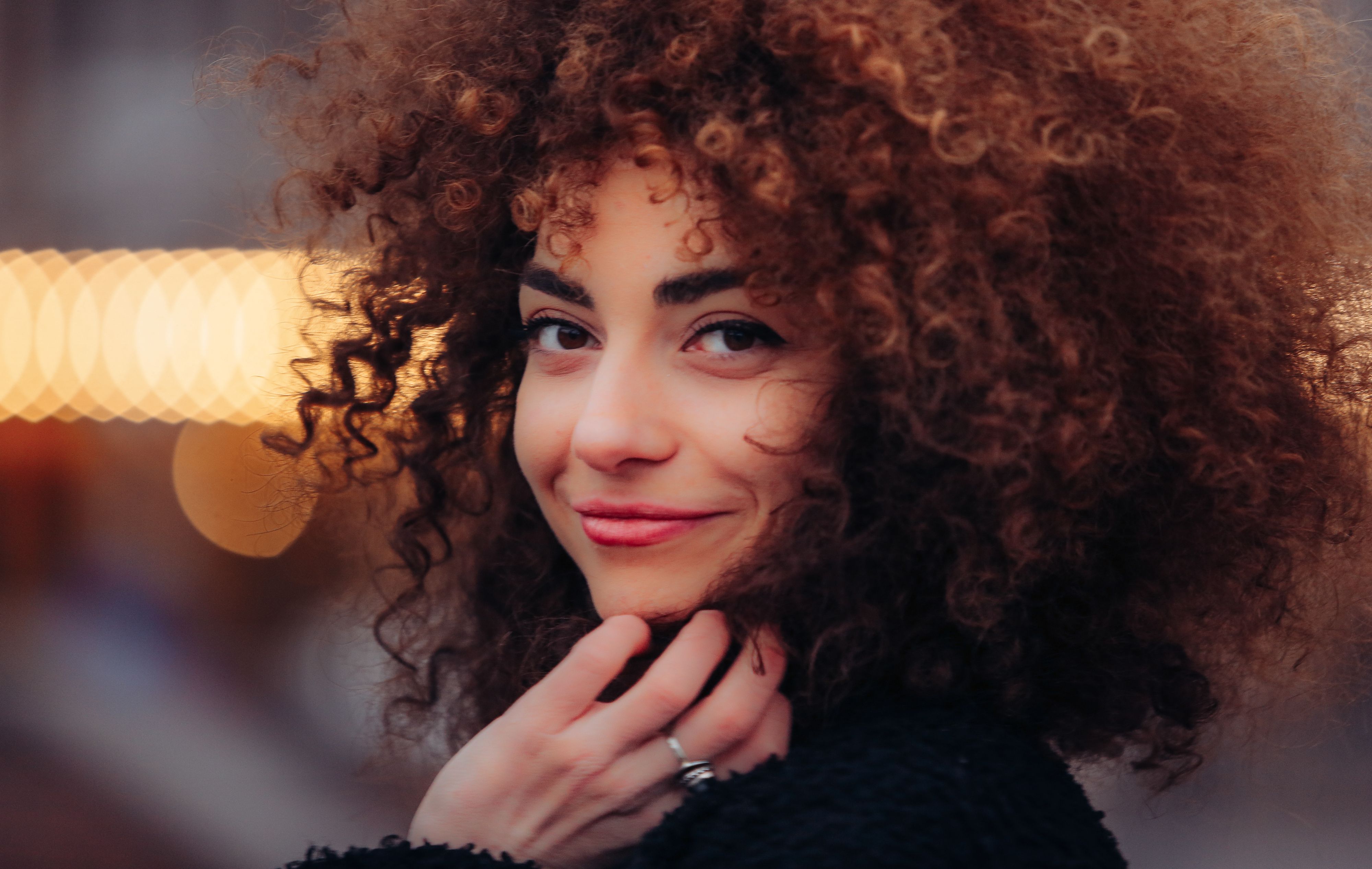 Illustrative editorial portrait of a woman with curly hair and a natural expression; photograph by Achi Murusidze on Pexels, not an AKOOL-generated result.