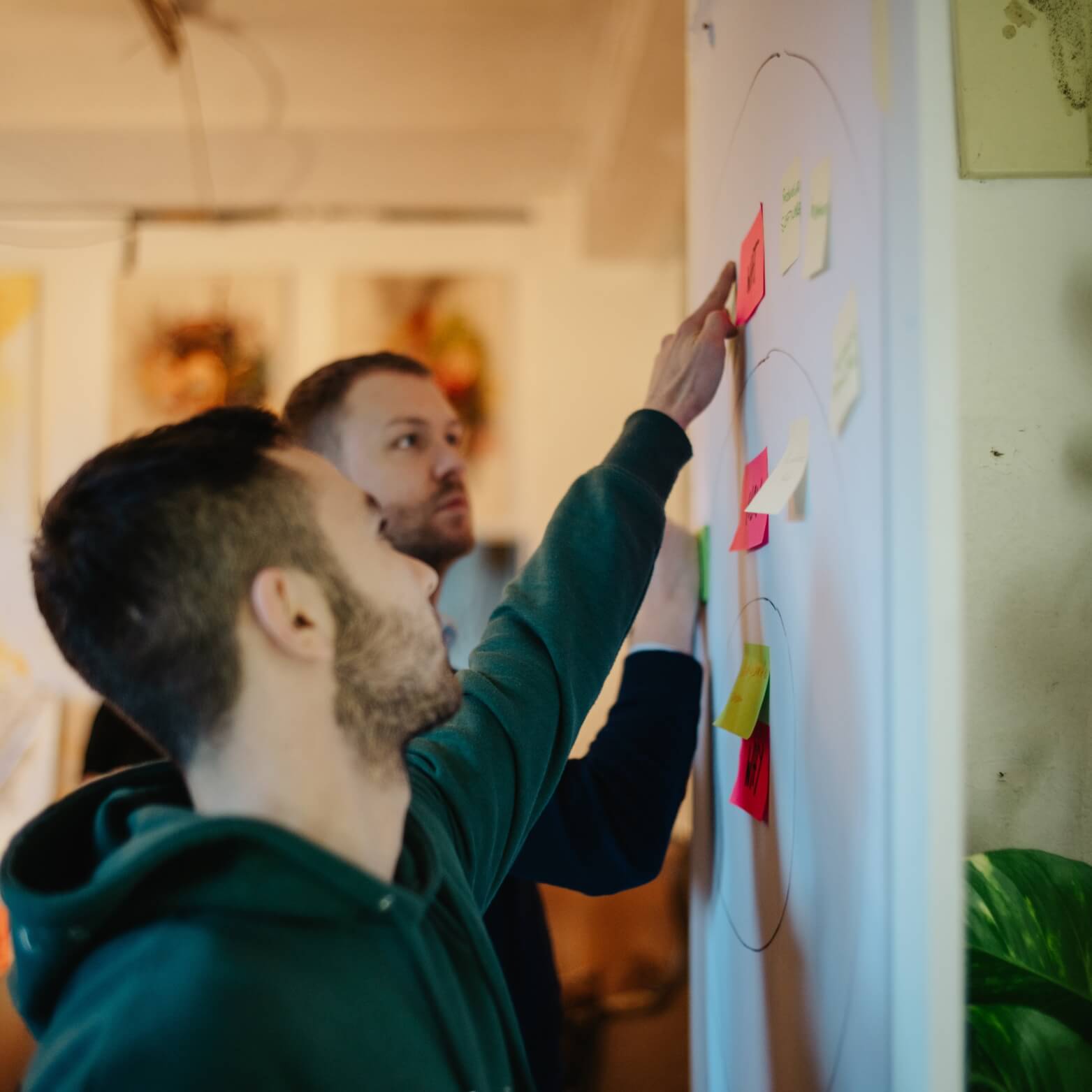 Personen sammeln Ideen an einer Wand mit Post it
