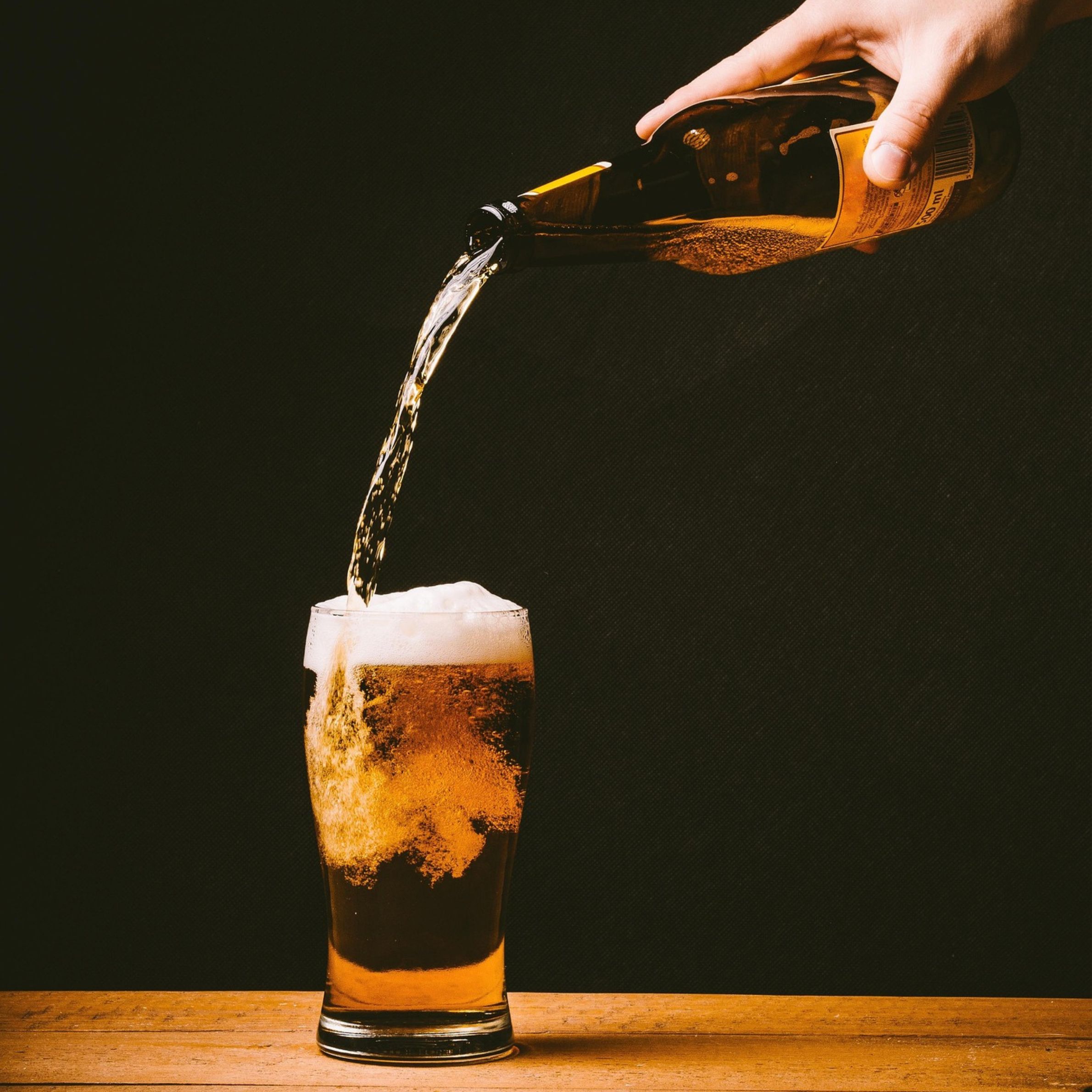 Bier wird von einer Flasche in ein Glas eingegossen