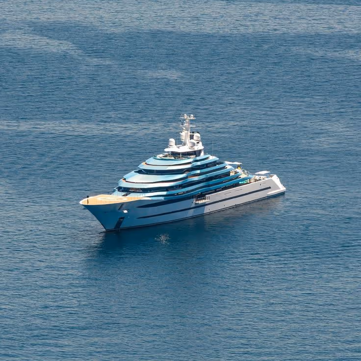 Luxury multi-deck yacht floating on calm blue sea waters.