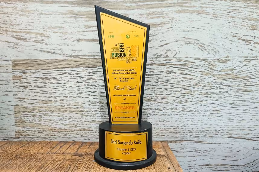Award trophy with yellow plaque honoring Shri Surjendu Kuila as Founder & CEO of Zopper, for participation as speaker at Fusion B2B Microfinance event 2022.