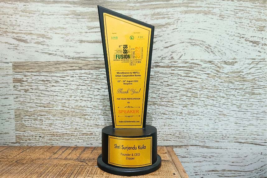 Award trophy with yellow plaque honoring Shri Surjendu Kuila as Founder & CEO of Zopper, for participation as speaker at Fusion B2B Microfinance event 2022.