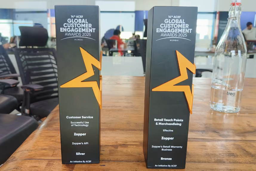 Two black awards with orange star designs for the 14th ACEF Global Customer Engagement Awards 2025 in Mumbai, recognizing Zopper for Customer Service Silver and Retail Touch Points Bronze.