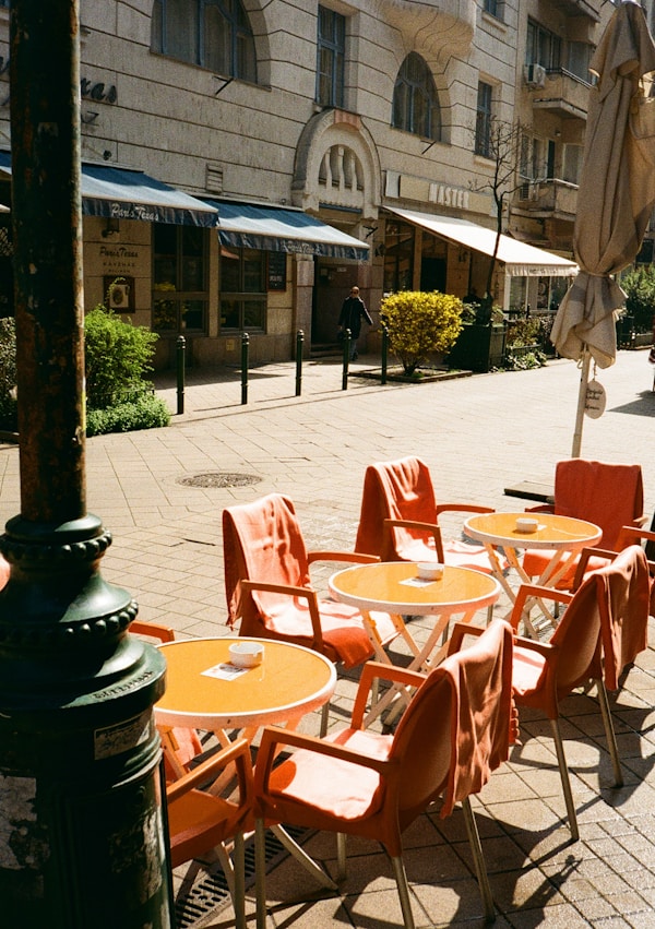 Outdoor cafe tables and chairs line a sunny street.